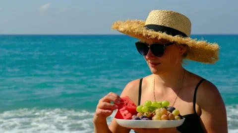 Woman on the beach eats fruit. Selective focus. Stock Footage 168664430