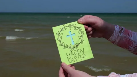 Woman at the Beach Holds Up a Happy Easter Card with Religious Christian Cross Video stock 320222644