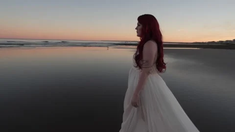 Woman on Beach Wearing White Dress at Sunset in slow motion Stock Footage