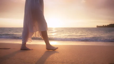 Woman in beautiful white dress at sunset Slow motion woman feet walking by beach Stock Footage