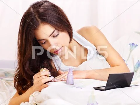 Woman in bed applying nail polish Stock Photos