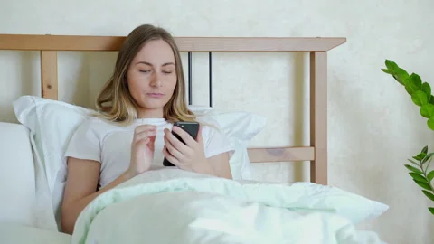 Woman in bed checking social apps with smartphone 库存影片 130849344