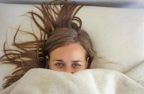 Woman in bed covered up to the face Stock Photos