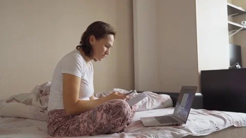 A woman in bed is scanning a barcode using a smartphone to pay for utilities Video stock 108976046