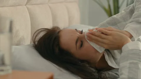 Woman on bed sneezing cough runny nose allergy bedroom home female girl Stock Footage 276201379