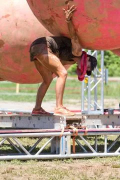Woman Bends Low To Avoid Ball Obstacle At Mud Run Stock Photos