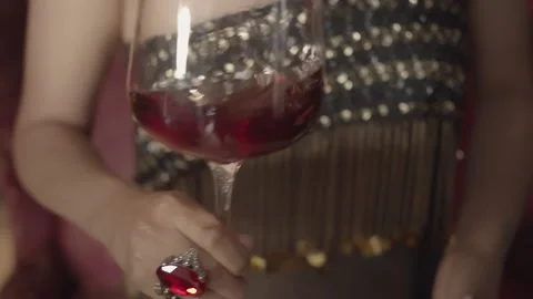 Woman with a big ring with a red ruby stone swirls a glass with red wine. Stock Footage 195200141