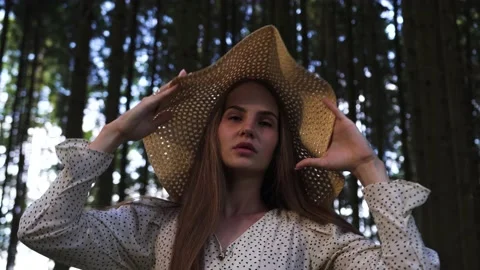 Woman in a big straw hat posing in the forest lifting her from her eyes Stock Footage 158755038