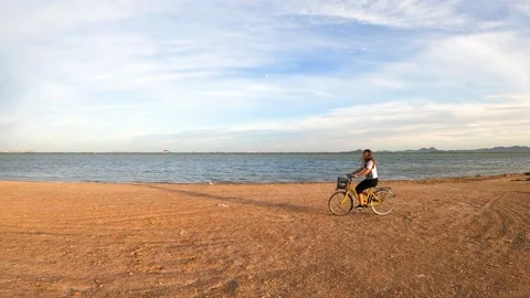 Woman biker going through the beach at sunset. Riding bike Video stock 140649953