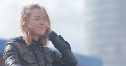 Woman biker starts motorcycle engine ready to ride sunny windy close up urban Stock Footage 85365553