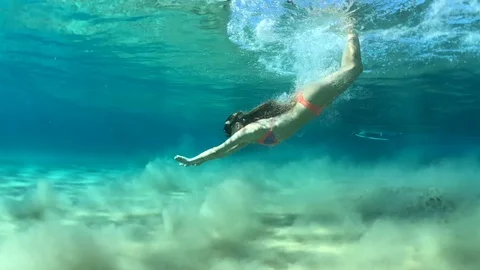 Woman in bikini diving under breaking wave in the tropics 動画素材 127633247