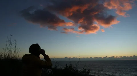 WOMAN WITH BINOCULARS SILHOUETTE AT SUNSET OR SUNRISE AT OCEAN Stock Footage 59071307