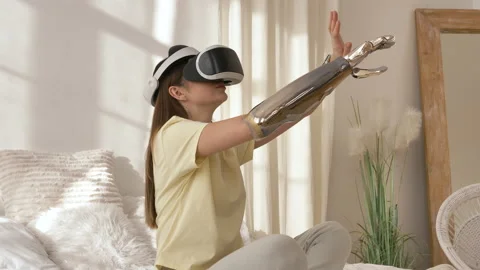 Woman with bionic arm and goggles plays video game on bed Stock Footage 150242292