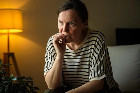 Woman biting her nails while struggling with stress and anxious thoughts at.. Stock Photos