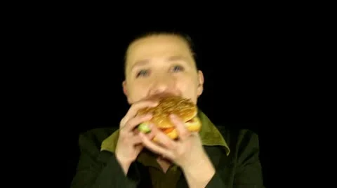 Woman on black background eats hamburger time lapse Stock Footage 10788368