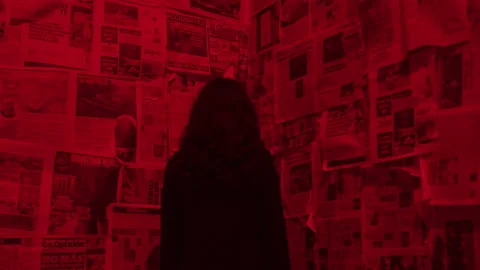 Woman in Black Faces Corner of Strobing Red Room Looking at Newspaper Clippings Stock Footage 208793728