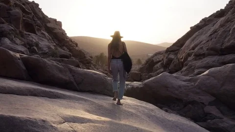 Woman in black hat walking on rocks in mountainous region Stock Footage