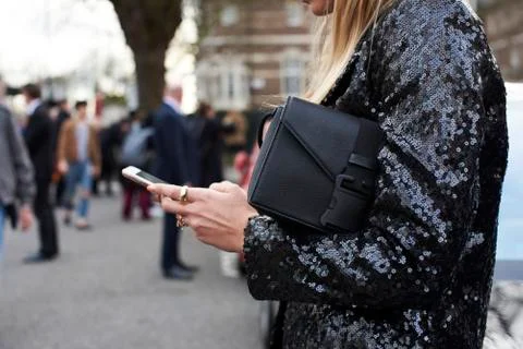 Woman in black sequinned jacket using smartphone in street, close up Stock Photos