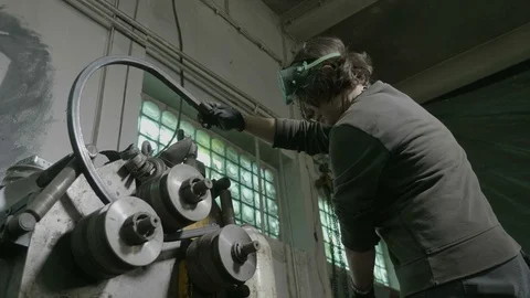 Woman blacksmith doing a bending test with an iron bar and a new bending mach Stock Footage 90649774