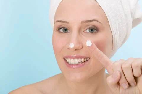 Woman with a blob of face cream on nose and finger Stock Photos