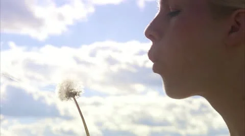 A woman blowing on a dandelion Stock Footage