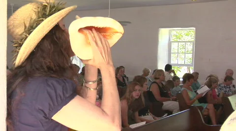 A woman blows a conch shell during a church service in Hawaii. Stock Footage 554223