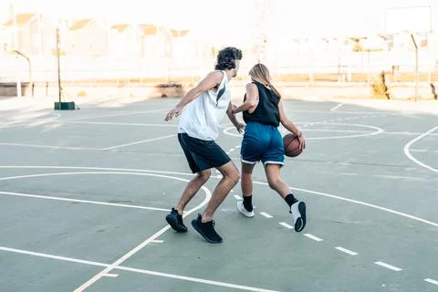 Woman bouncing a ball while playing basketball on an outdoor court Stock Photos
