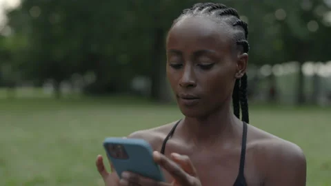 Woman with braids using mobile while resting during training Stock Footage 167096295
