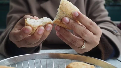 Woman breaks bread roll in half to share at outdoor cafe table footage. Stock Footage 332034156