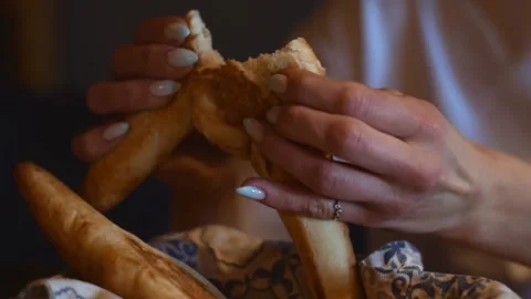 A woman breaks a bread roll with her hands in a cafe. Stock Footage 151977254