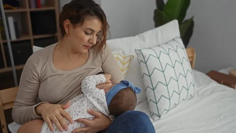Woman breastfeeding baby on bed with pat... | Stock Video | Pond5