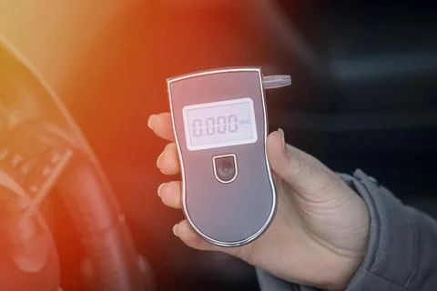 A woman with a breathalyzer in the car, testing for alcohol Stock Photos