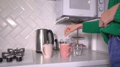 Woman brews tea in cup using tea bag in kitchen. Stock Footage 231330053