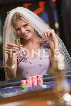 Woman in bridal veil in casino playing roulette and smiling (selective focus) Stock Photos