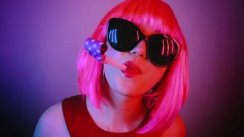 Woman in a bright pink wig at a party. She is blowing at a party horn. Stock Footage 113996953