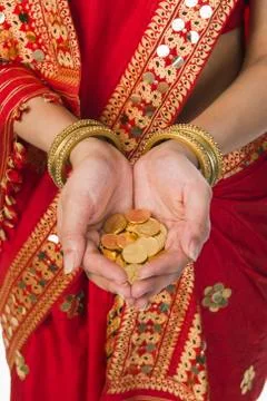 Woman in bright red mekhla holding gold coins Stock Photos