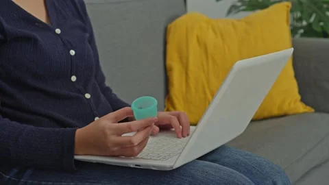 Woman browsing internet on laptop computer while holding green silicone Stock Footage 340575932
