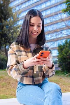 Woman browsing the internet using mobile device outdoors. Stock Photos