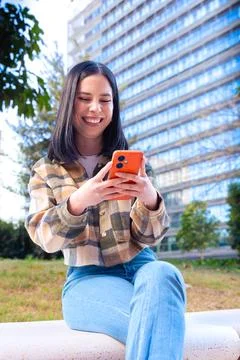 Woman browsing the internet using mobile device outdoors. Stock Photos