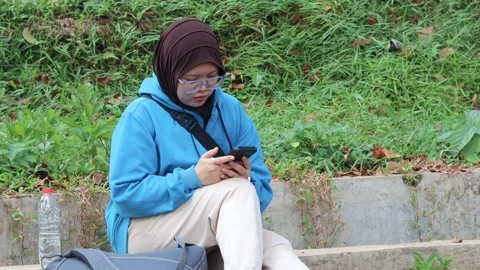 Woman browsing on a smartphone while relaxing outdoors Stock Footage 337150126
