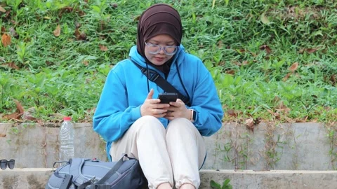 Woman browsing on a smartphone while relaxing outdoors Stock Footage 337150166