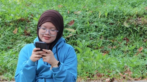 Woman browsing on a smartphone while relaxing outdoors Stock Footage 337150167