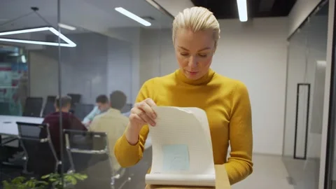 Woman browsing through notes in notepad Stock Footage 132941680