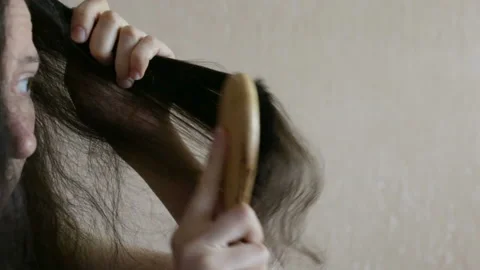 A woman brushes a strand of long dark hair. Close-up, indoors, real time Stock Footage 91906053