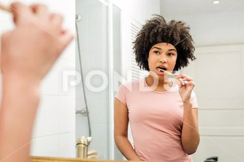 Woman brushing her teeth. Girl with bamboo brush in front of the mirror. Stock Photos