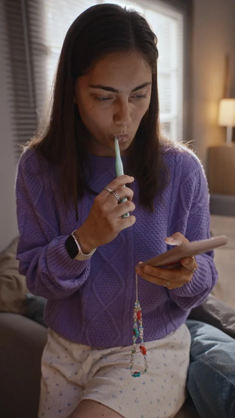 Woman Brushing Teeth While Addicted to Scrolling Smartphone Stock Footage 344122906
