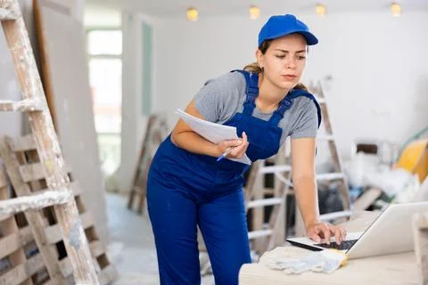 Woman builder checking documentation, using laptop Stock Photos