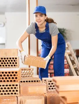 Woman builder stacking red bricks inside building under construction Stock Photos