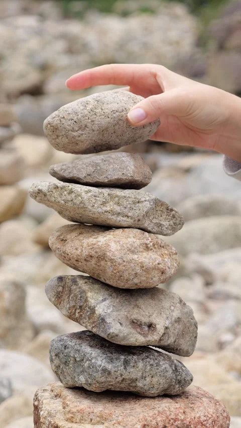 Woman building a cairn, adding one more stone Stock Footage 303984433