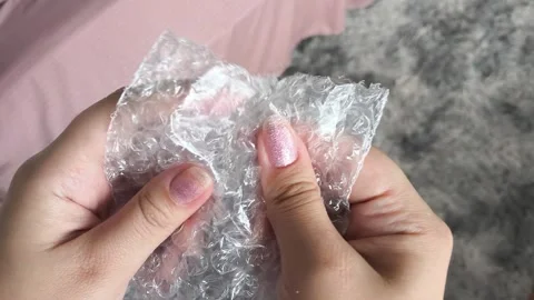 Woman bursts bubbles on a packaging bubble wrap, trying to calm down. Burst the Stock Footage 314974456